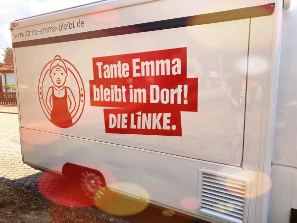 Rückwand des mobilen Dorfladens mit dem Text "Tante Emma bleibt im Dorf! - DIE LINKE"